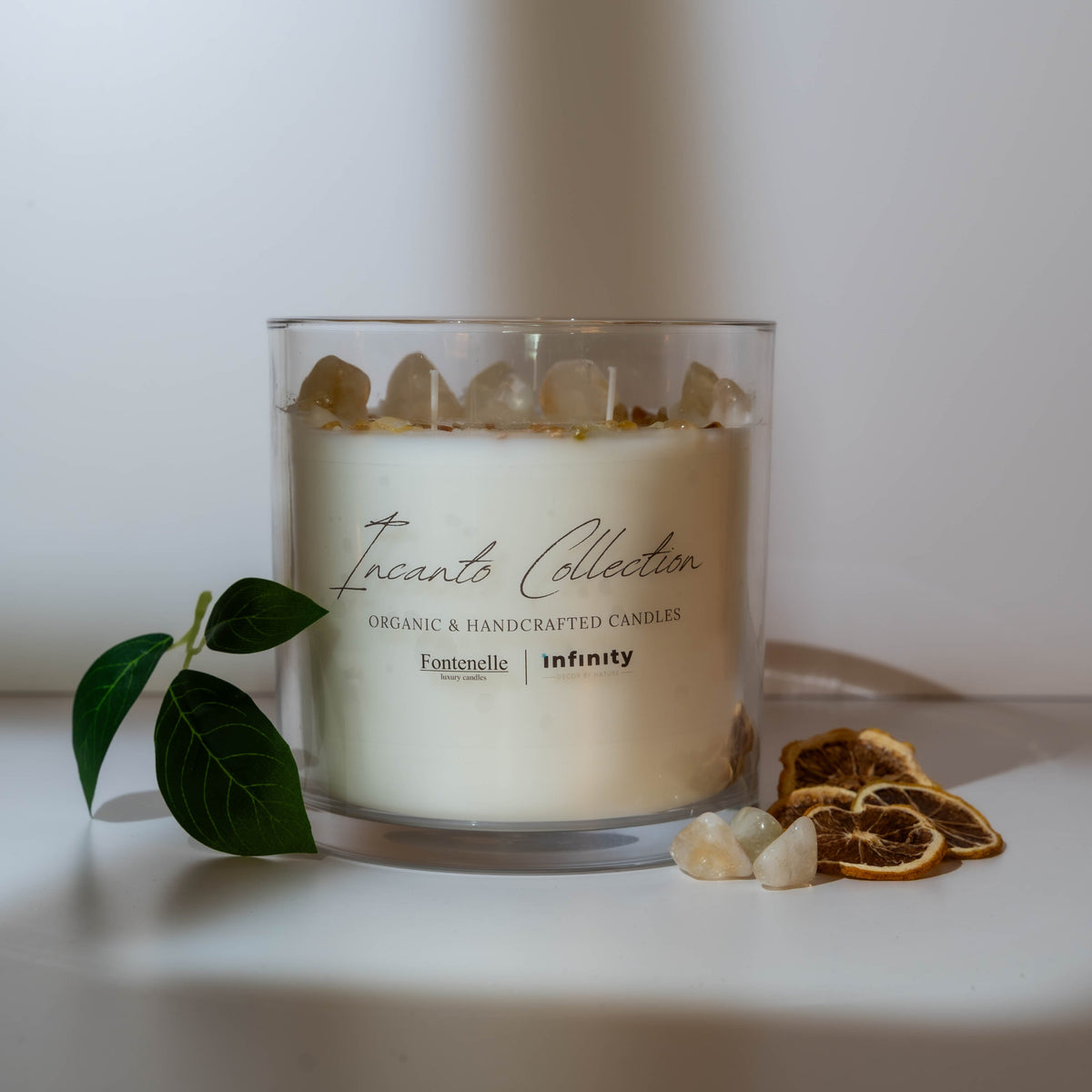 Incanto 55 oz centerpiece candle in a clear glass vessel, styled with natural gemstones on a white table