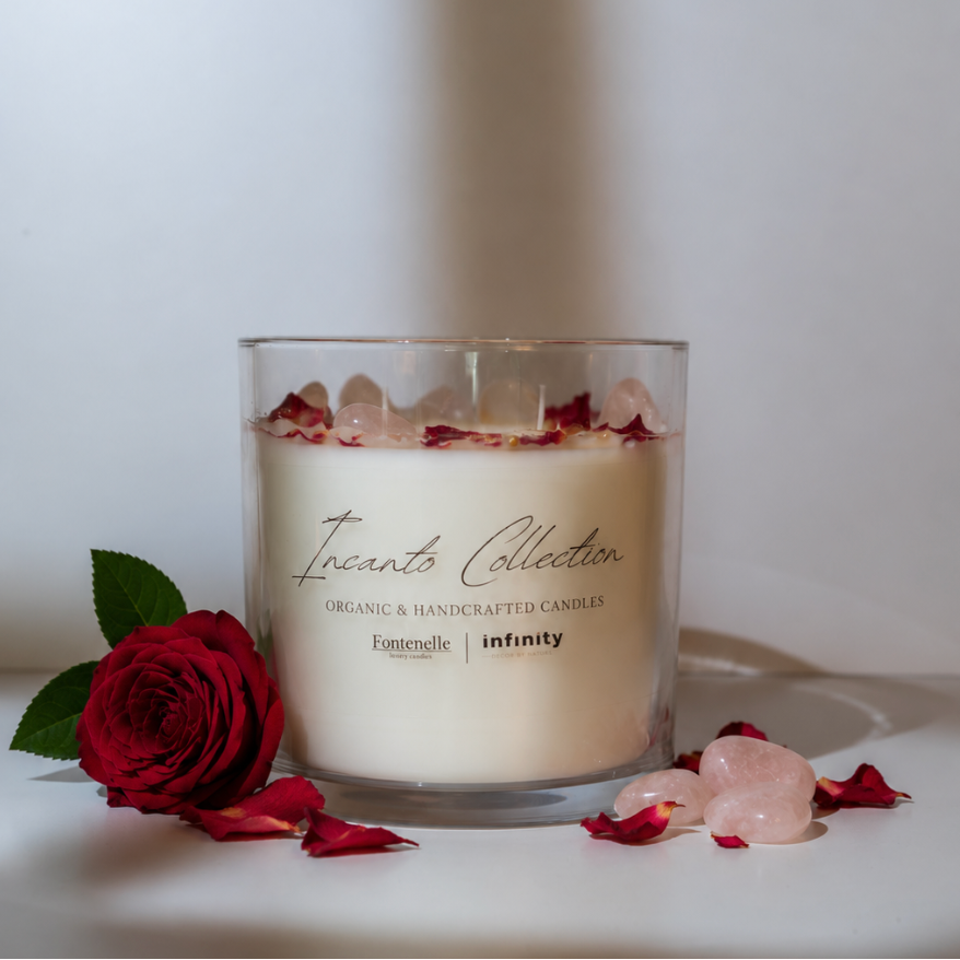 Incanto Amore 55 oz centerpiece candle in a glass vessel, styled with a red rose and rose quartz stones