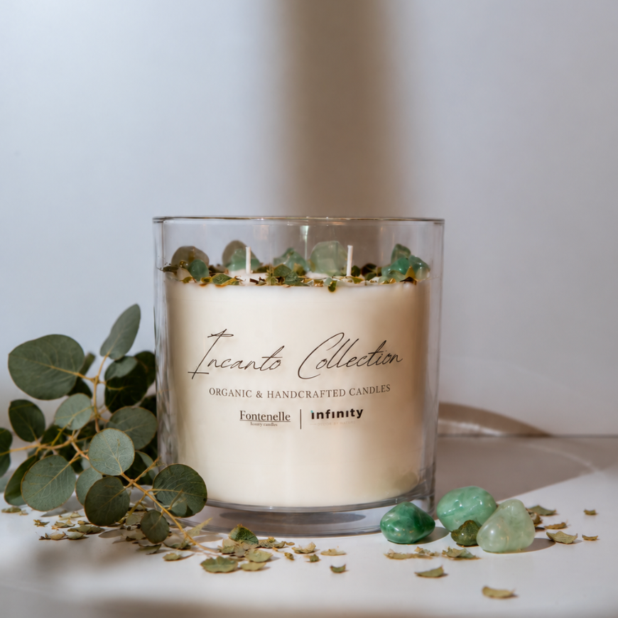 Incanto Vita 55 oz centerpiece candle in a clear glass vessel, styled with eucalyptus leaves and green aventurine stones