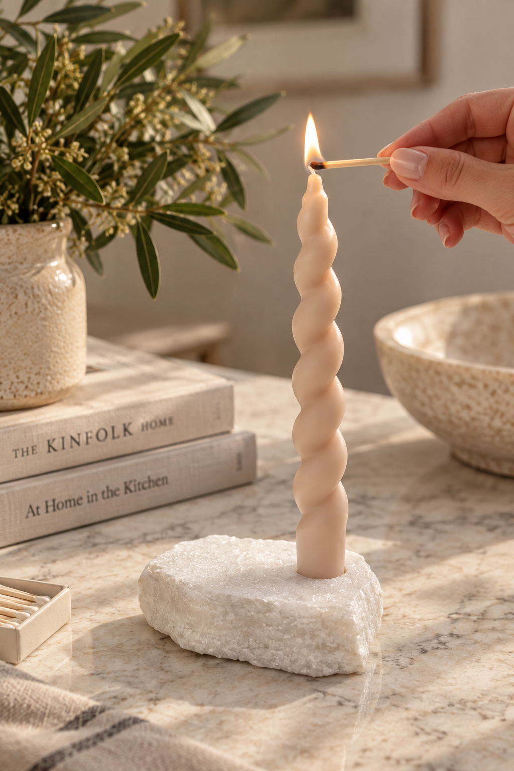 White marble taper candle holder with twisted candle being lit