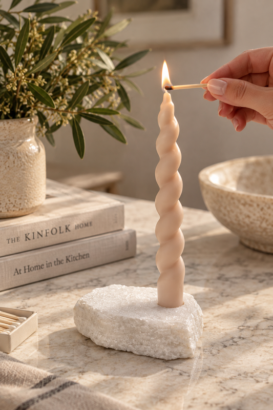 White marble taper candle holder with twisted candle being lit
